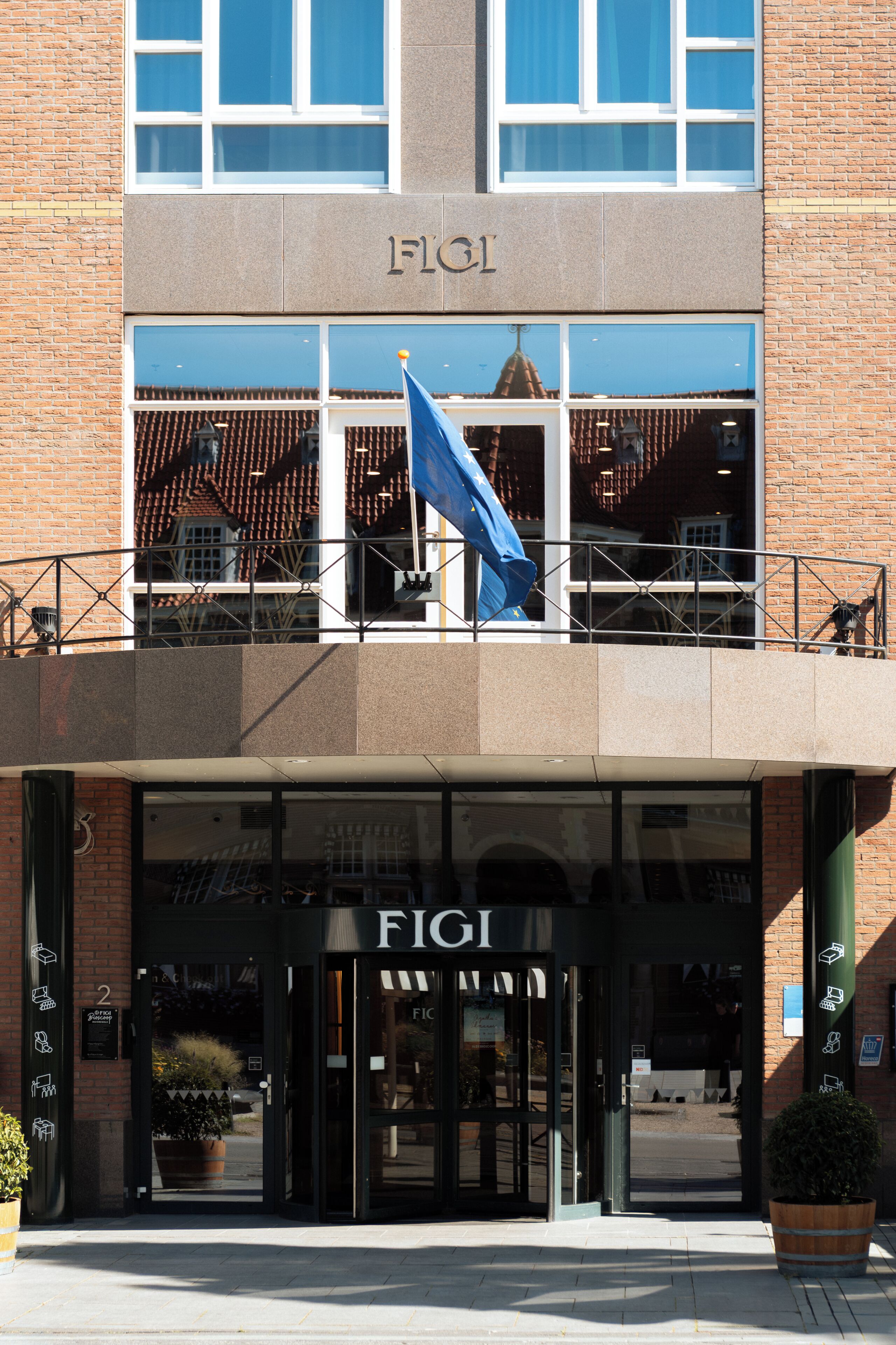 Un edificio con un llamativo letrero 'FICI' sobre la entrada, una bandera azul y fachada de ladrillo.