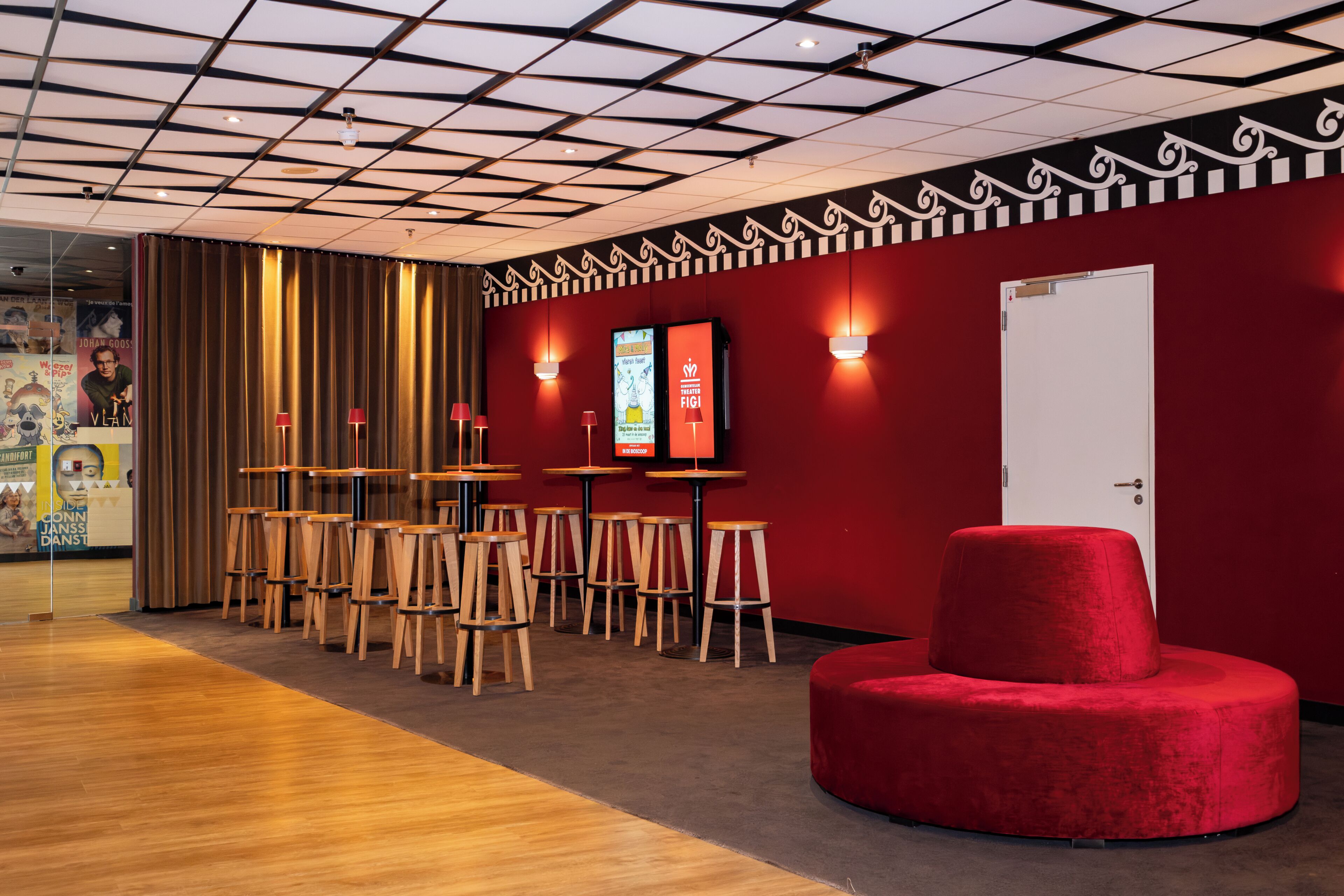 A modern interior with a red wall, wooden tables, and a red ottoman.