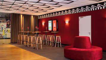 A modern interior with a red wall, wooden tables, and a red ottoman.