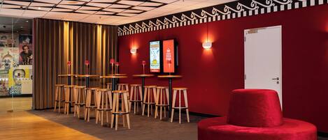 A modern interior with a red wall, wooden tables, and a red ottoman.