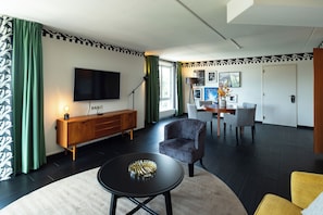 Una sala de estar moderna con un televisor de pantalla plana, un mueble de madera, una mesa redonda y una zona de comedor con sillas y una mesa.