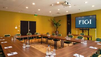 A conference room with a long table, chairs, a projector, and a screen displaying 'FIGI'.
