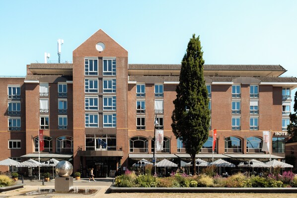 Un hotel con un patio central, mobiliario exterior y una gran fuente decorativa.