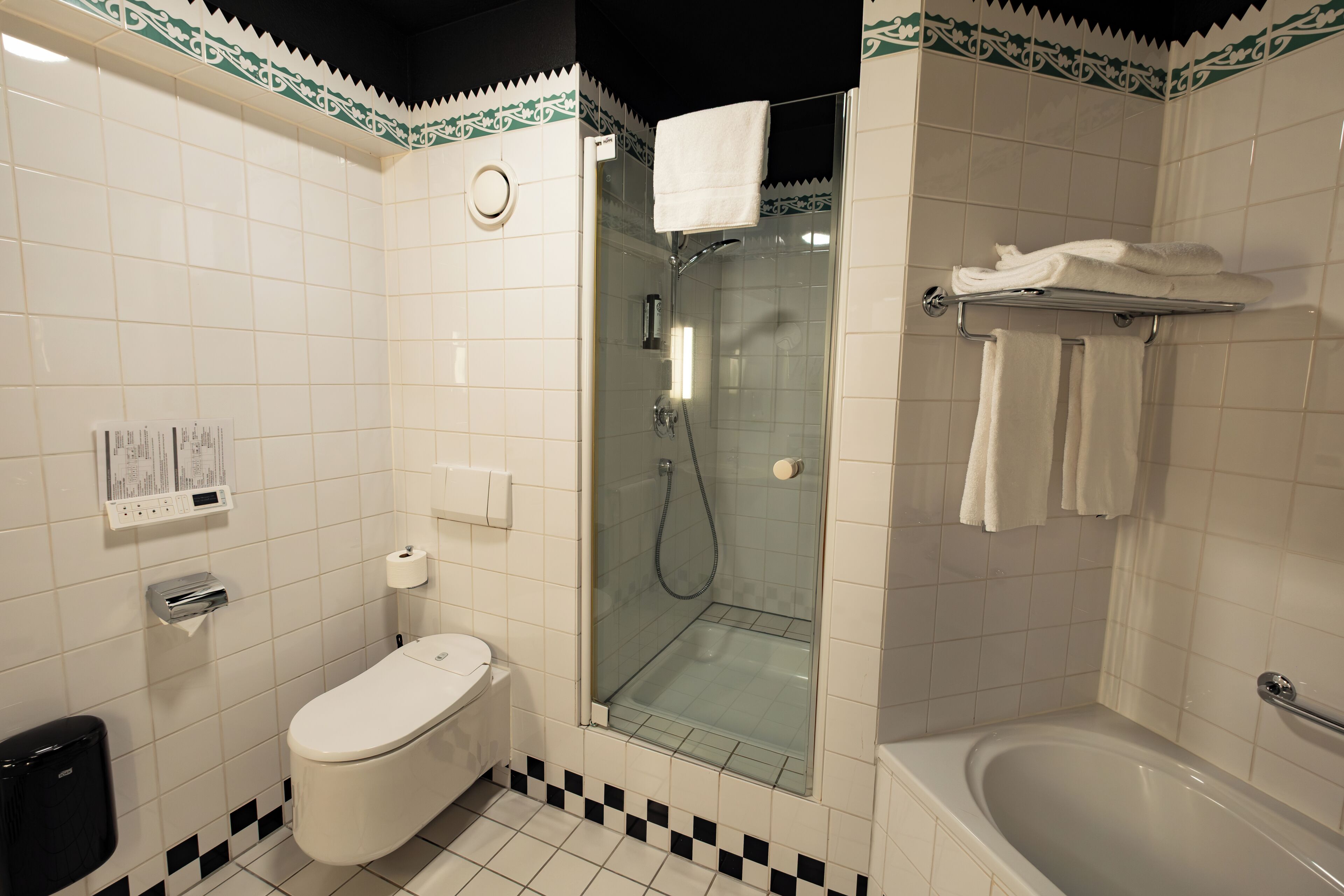 Een badkamer met toilet, douchecabine en bad.