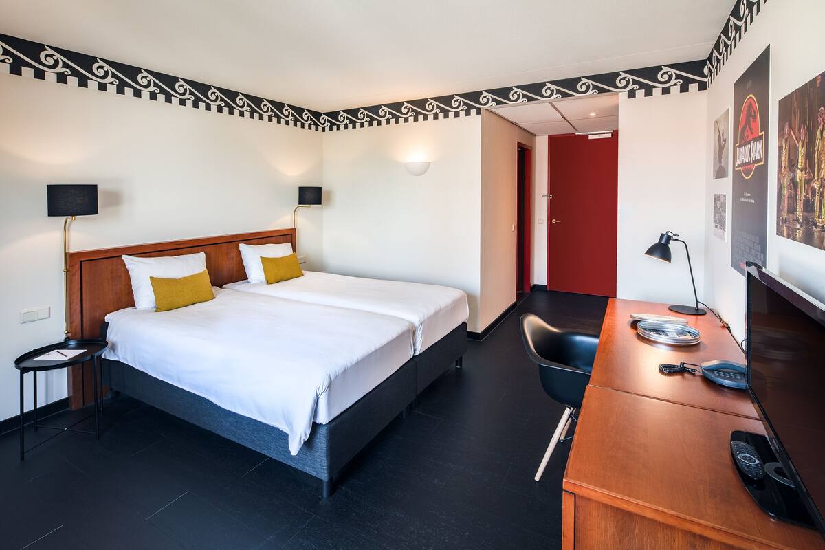 A hotel room with a bed, bedside tables, a desk, and a chair.