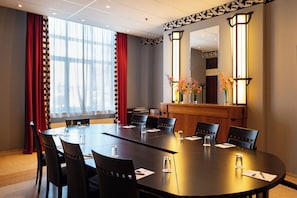 A conference room with a long table, chairs, and a reception desk with a vase of flowers. - Hotel Theater Figi (Zeist)
