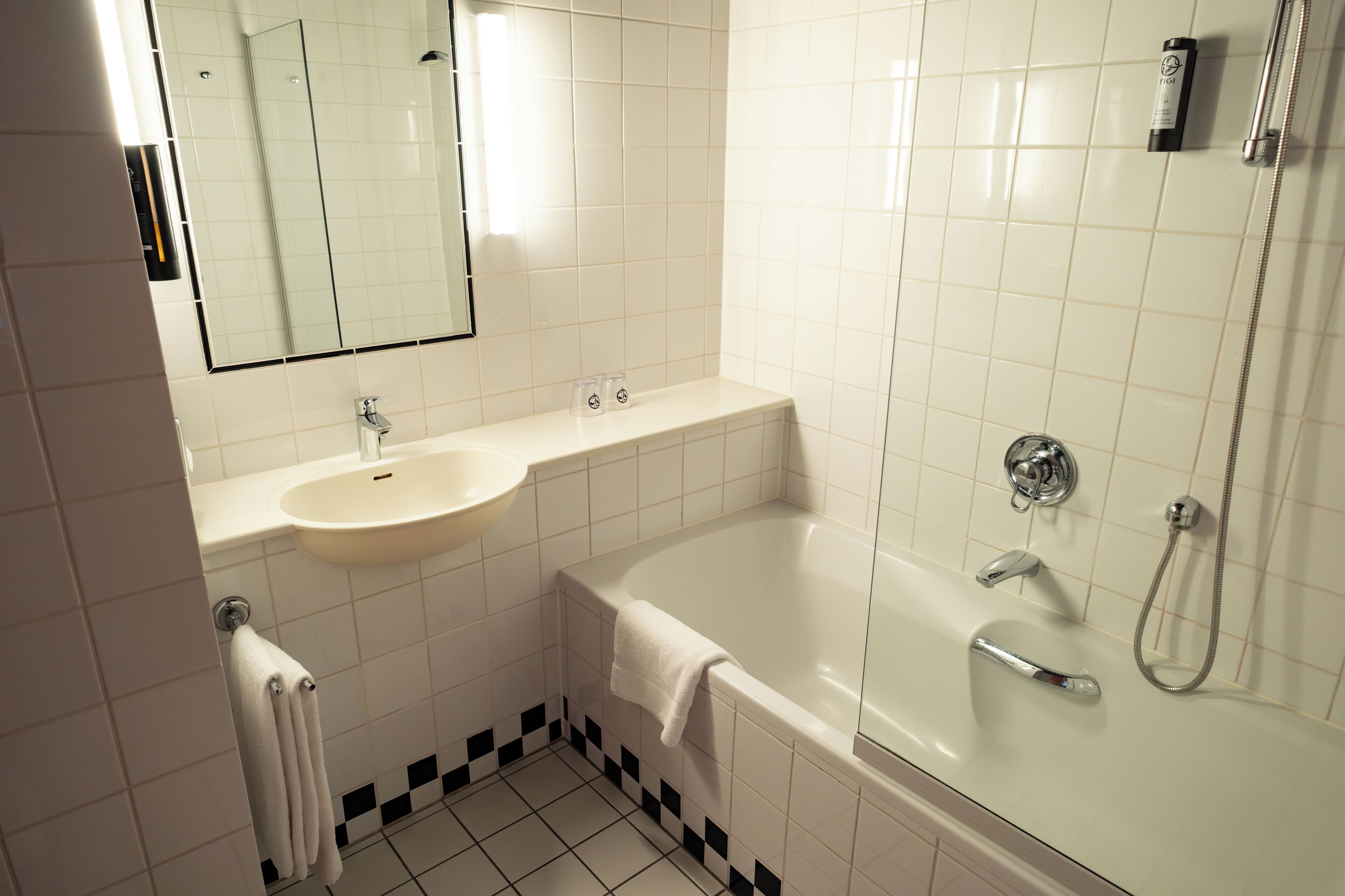 Un baño con lavamanos, espejo, bañera y ducha.