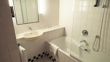Un baño con lavamanos, espejo, bañera y ducha.