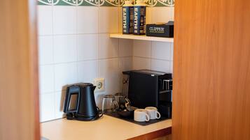 Een kitchenette met een koffiezetapparaat, een waterkoker en een koffiemachine. Op het aanrecht staan ook twee mokken.