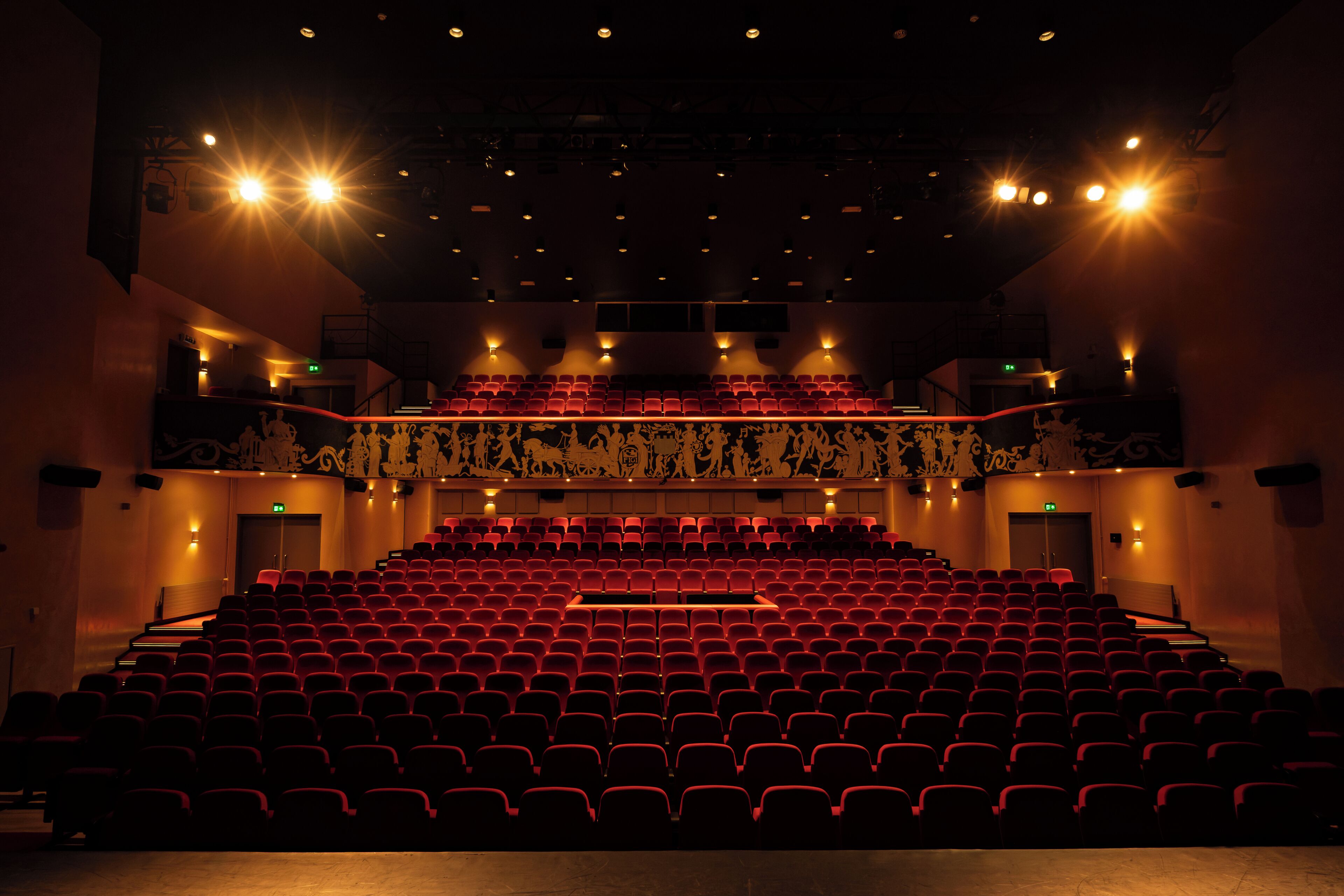 Un auditorio interior con asientos escalonados y múltiples salidas.