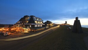 A modern hotel with a multi-story structure, a parking area, and a view of the beach. - Grand Hotel Beatrix (Huisduinen)