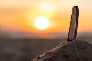 A wooden post in a sandy area with a sunset in the background. - Grand Hotel Beatrix (Huisduinen)