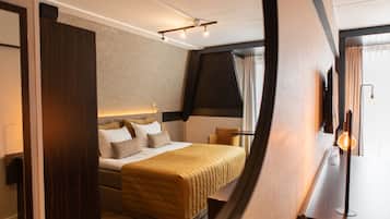 A modern hotel room with a large bed, a desk with a lamp, and a view of the outdoors through the window.