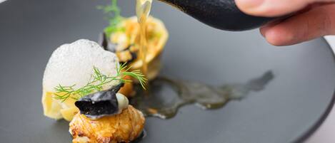 A dish with seafood and a sauce being poured over it.