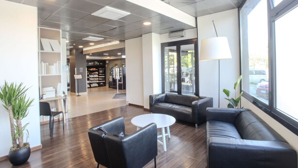 A modern lobby with leather sofas, a white table, and a potted plant. - B&B Hotel Firenze Novoli (Florence)