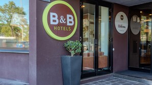 A B&B hotel entrance with a large sign, a potted plant, and a glass door leading inside. - B&B Hotel Firenze Novoli (Florence)
