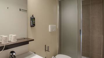 Un baño con lavamanos, inodoro y cabina de ducha de vidrio.