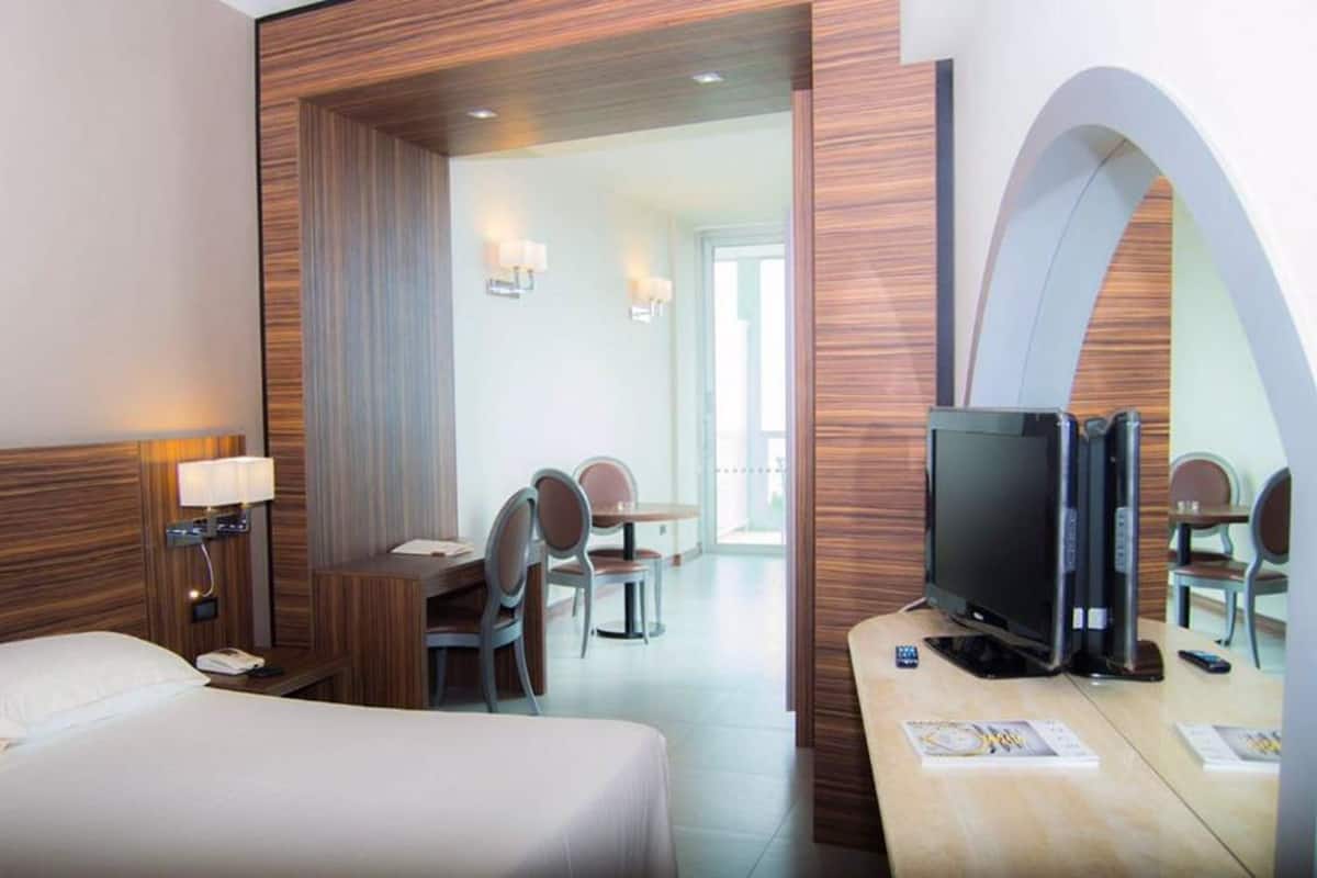 Une chambre d’hôtel avec un lit, un bureau avec une télévision, une chaise et une table.
