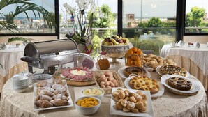 Mesa de buffet com diversos alimentos e vista para o exterior.