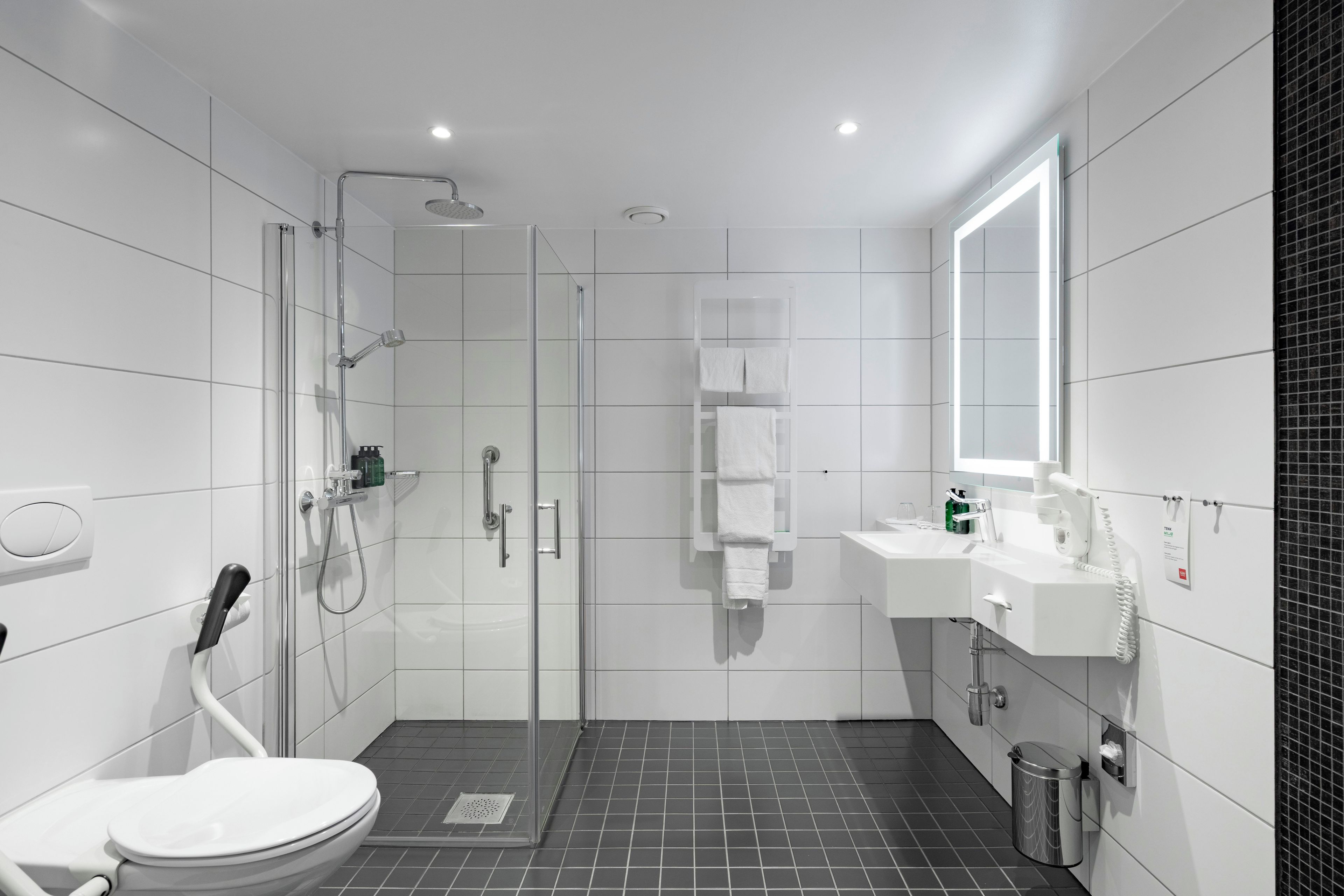 A modern bathroom with a toilet, shower, and sink.