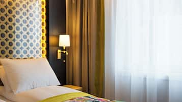 Una habitación de hotel con una cama, una mesita de noche, una lámpara y cortinas.