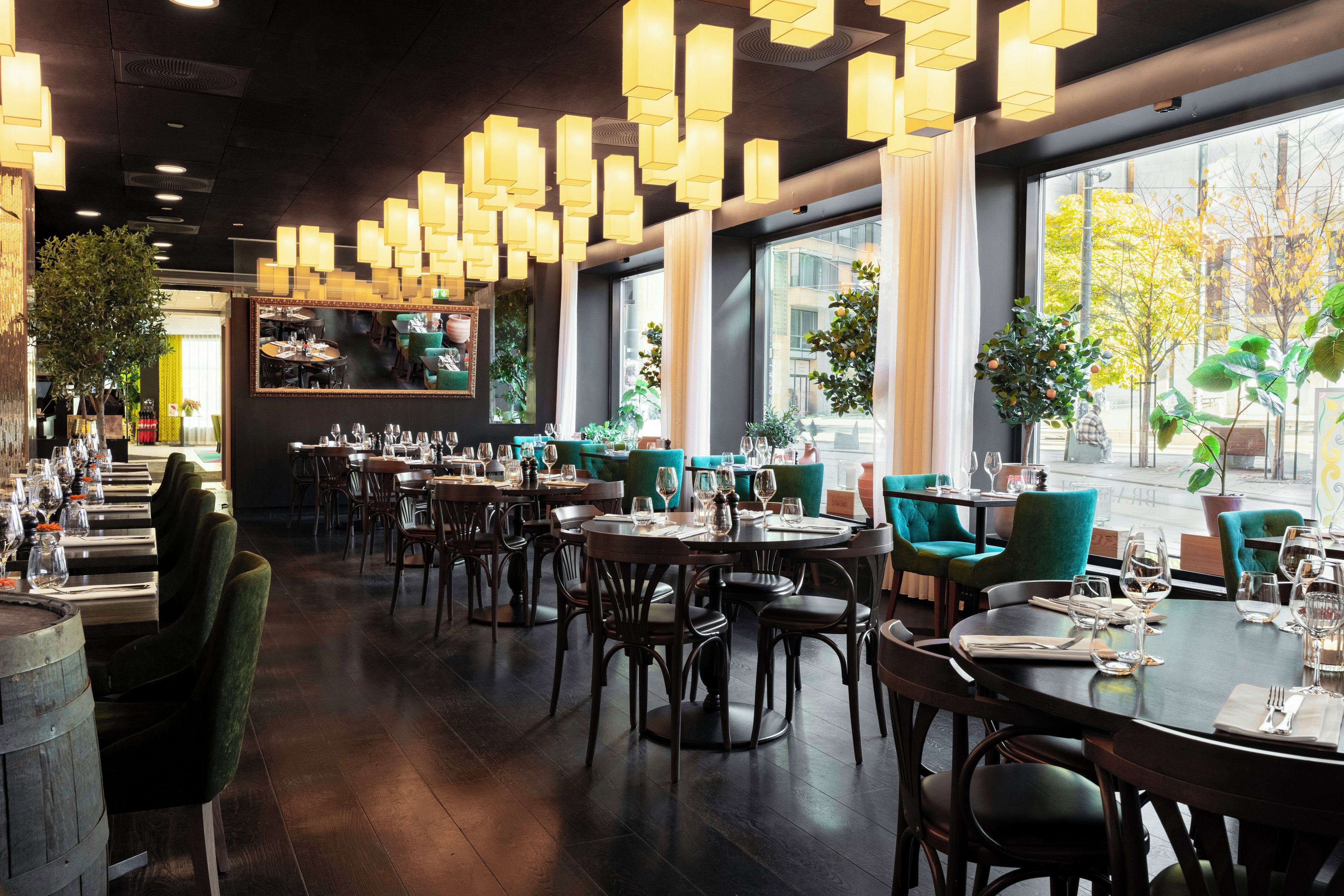 A restaurant interior with multiple dining tables, chairs, and hanging pendant lights.