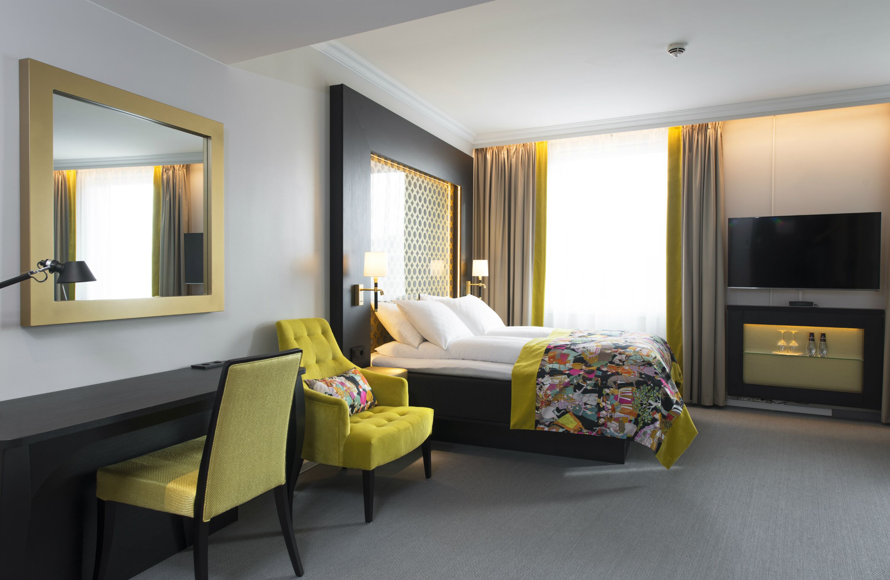 A hotel room with a bed, a desk, a chair, a television, and a window with curtains.
