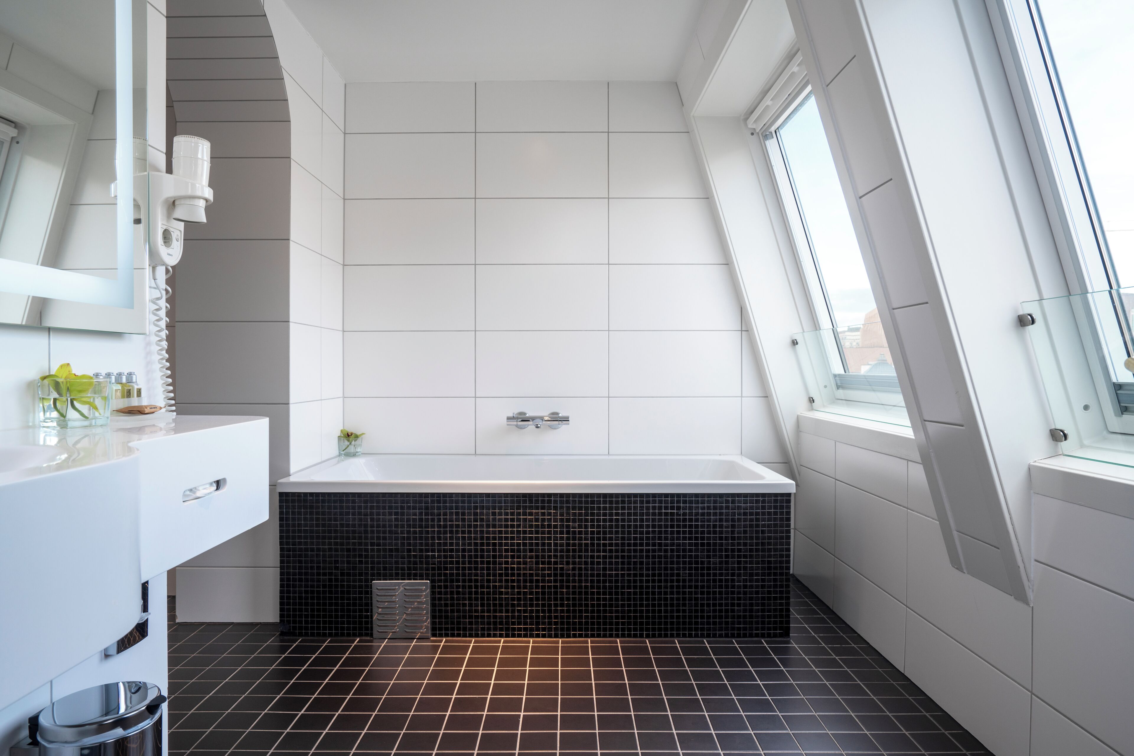 Ein modernes Badezimmer mit Badewanne, Waschtisch und Fenster.