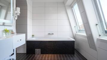 Ein modernes Badezimmer mit Badewanne, Waschtisch und Fenster.