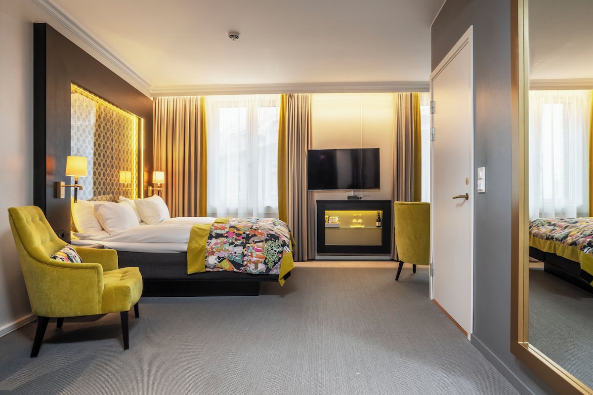 A hotel room with a bed, a television, a desk with a computer, a chair, and a mirror.