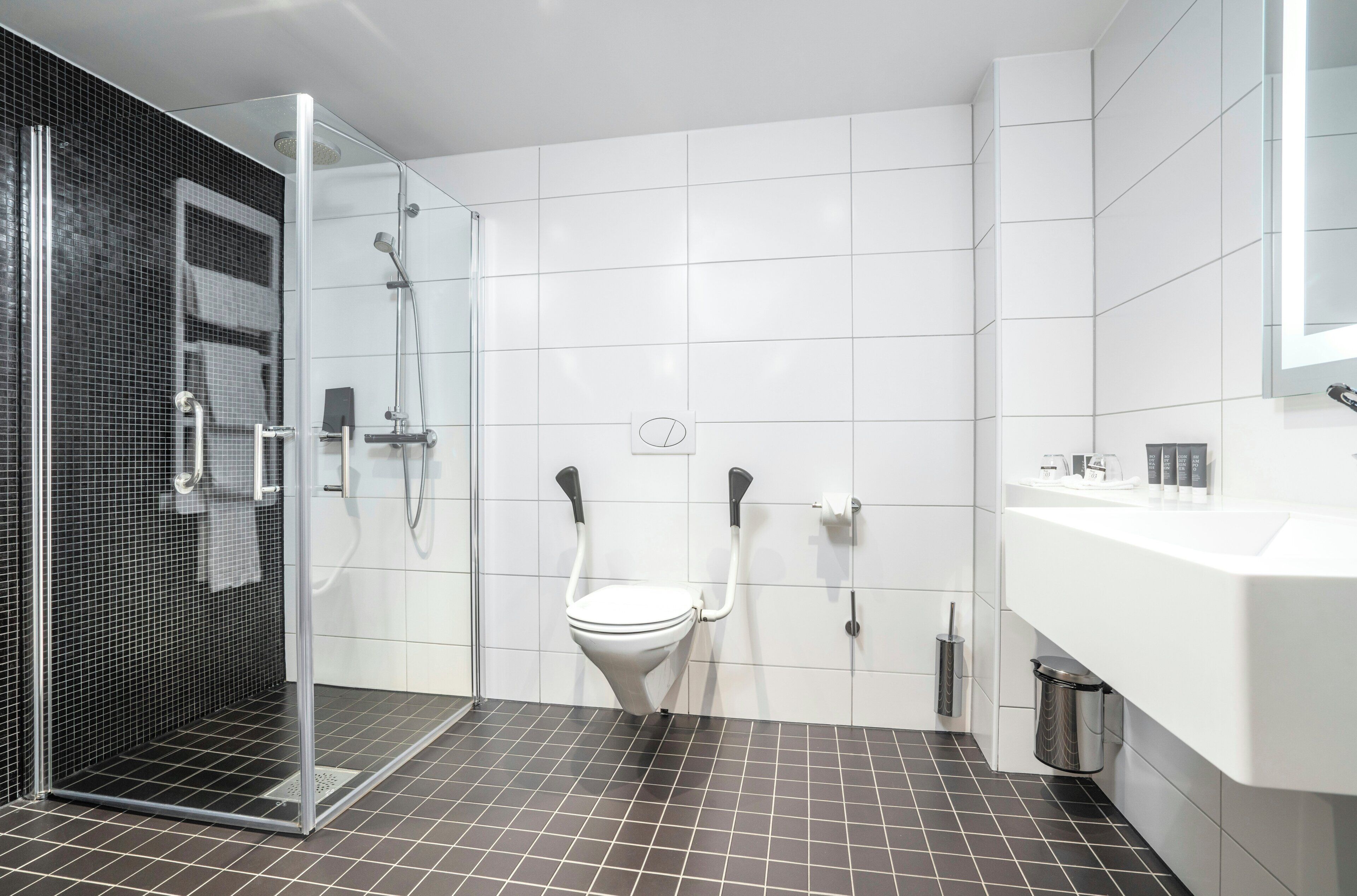 A modern bathroom with a shower, toilet, and sink.