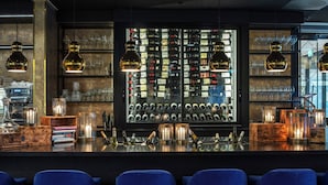 Eine Bar mit Weinkühler, Barhocker und Pendelleuchten.