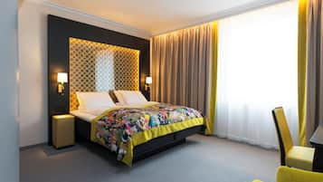 A hotel room with a bed, bedside lamps, a chair, and a window with curtains.