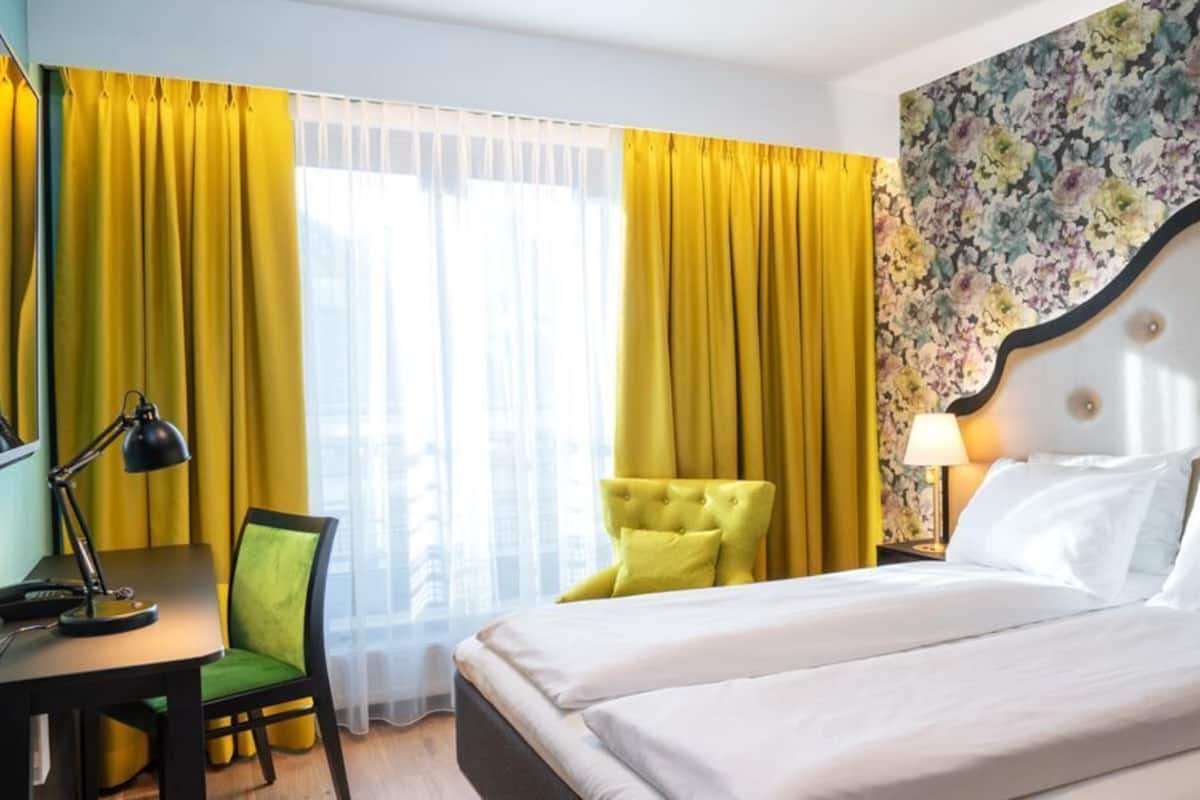 Una habitación de hotel con cama, escritorio, silla y lámpara.