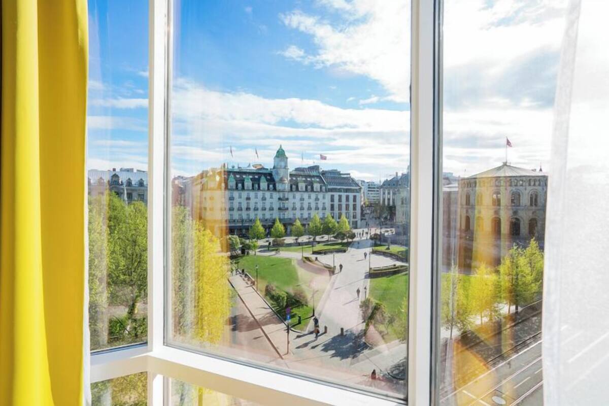 A view from a window overlooking a large building with a central courtyard and surrounding trees.
