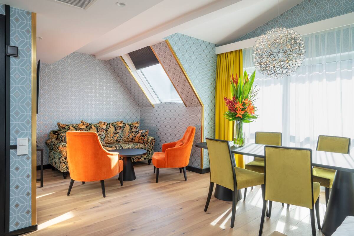 A dining area with a table and chairs, a sofa, and a decorative vase with flowers.