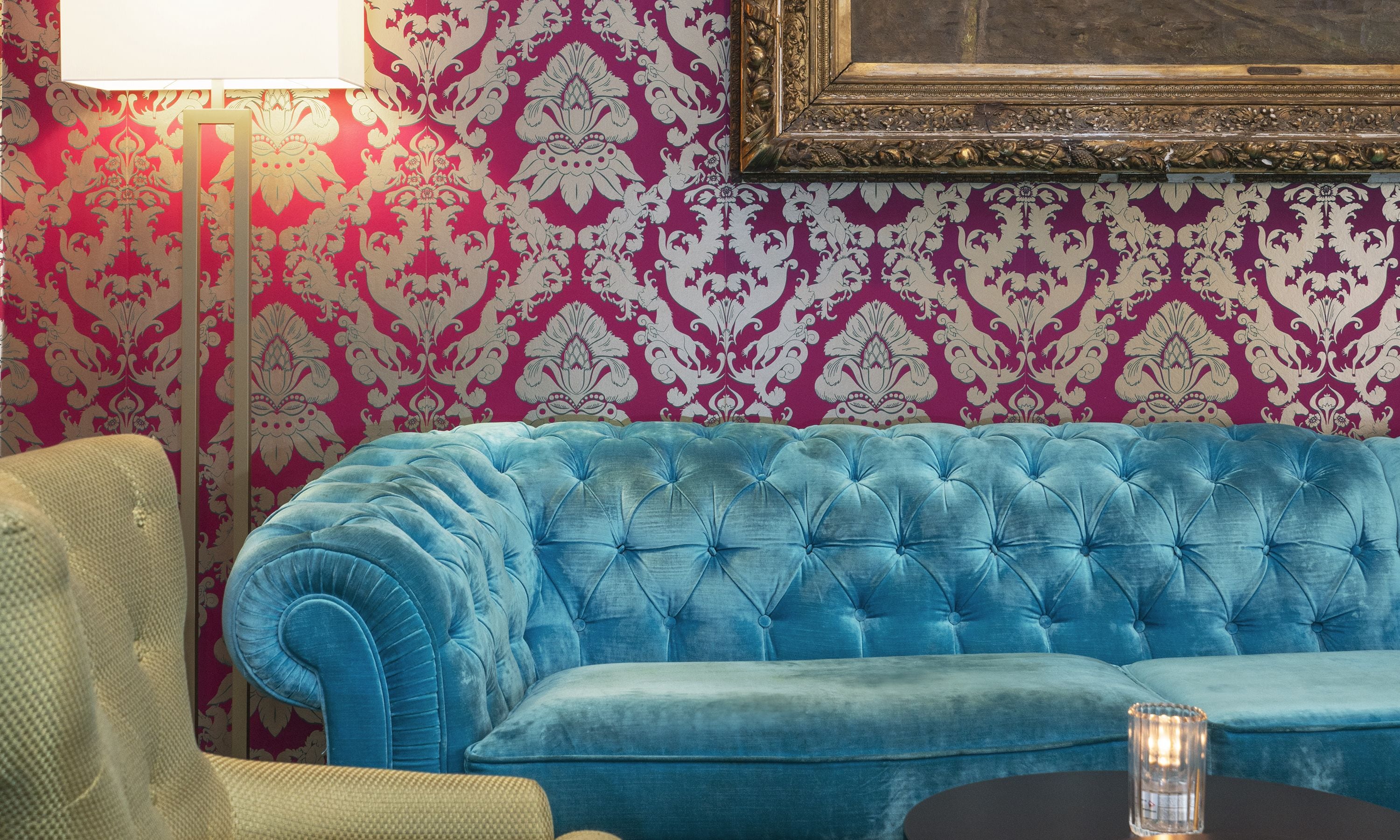 Une pièce avec un canapé bleu, une lampe et un papier peint à motifs.