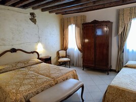 Una camera da letto con due letti, un armadio in legno, una sedia e un comodino.