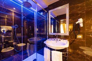 Un baño lujoso con ducha envuelta en vidrio, un espejo grande y dos lavamanos.