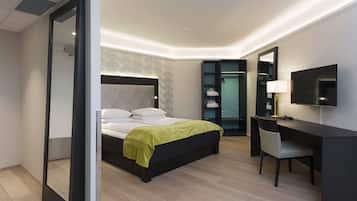 Een moderne hotelkamer met een groot bed, een bureau met stoel, een televisie en een inloopkast.