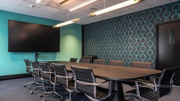 A conference room with a large table, chairs, a screen, and patterned walls.