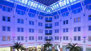 Un atrium à plusieurs niveaux, doté d’une verrière, de nombreux  étages et d’un espace central ouvert agrémenté de palmiers.