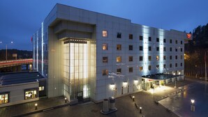 Un hôtel moderne doté d’une façade en verre, de plusieurs étages et d’une entrée bien éclairée.