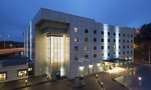 Welcome to our hotel, featuring a striking entrance with large glass doors and a grid of windows.