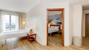 Une chambre d’hôtel avec une grande fenêtre, un lit, une table de chevet et une vue sur un port de plaisance.