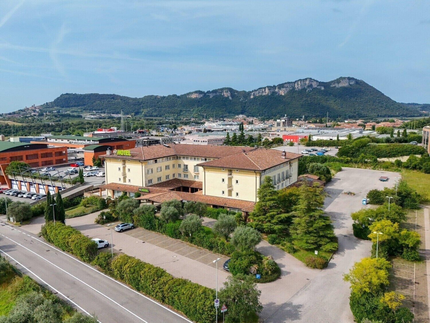 A hotel with a central courtyard, surrounded by greenery and a parking lot.