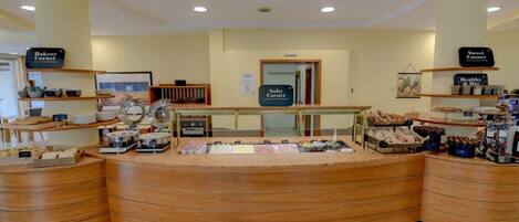 A bakery counter with various baked goods and a coffee station.