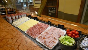 Un comptoir de charcuterie proposant une variété de viandes, de fromages et de légumes.
