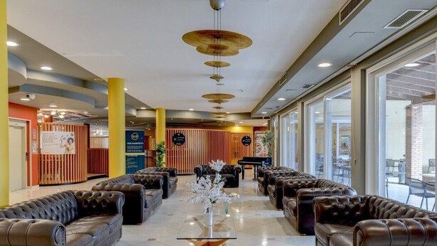 Un hall d’entrée avec des canapés en cuir, une table basse en verre et un piano.
