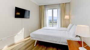Une chambre d’hôtel avec un lit, une télévision, une fenêtre avec des rideaux et une vue sur l’extérieur.
